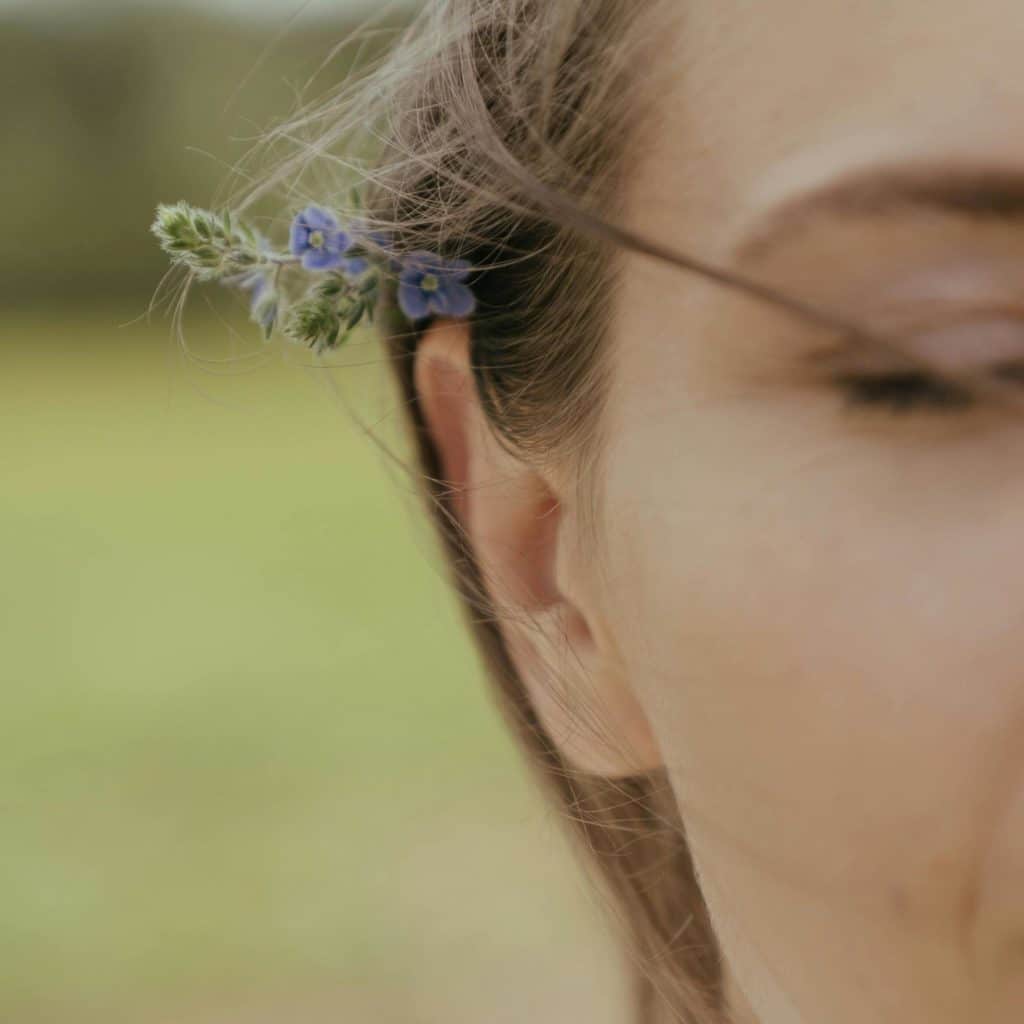 Une femme écoute, elle a une fleur de lavande sur l'oreille