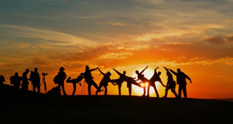 Un groupe de personnes faisant des ombres devant un soleil couchant